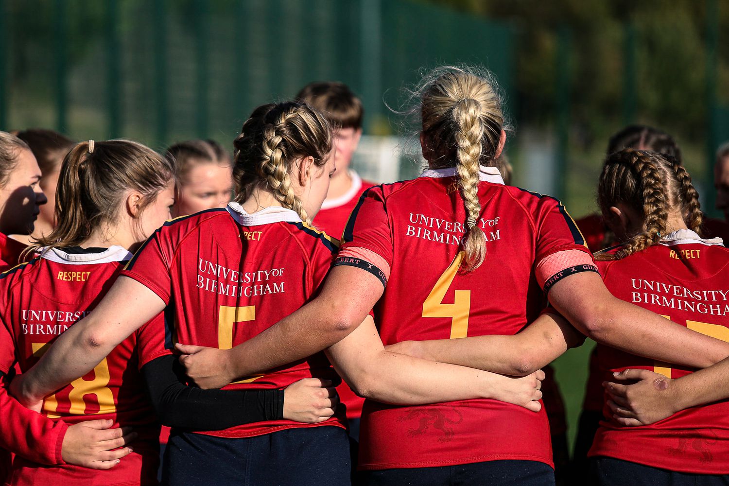 Team huddle showing red jerseys and uniform backs during a sports match.