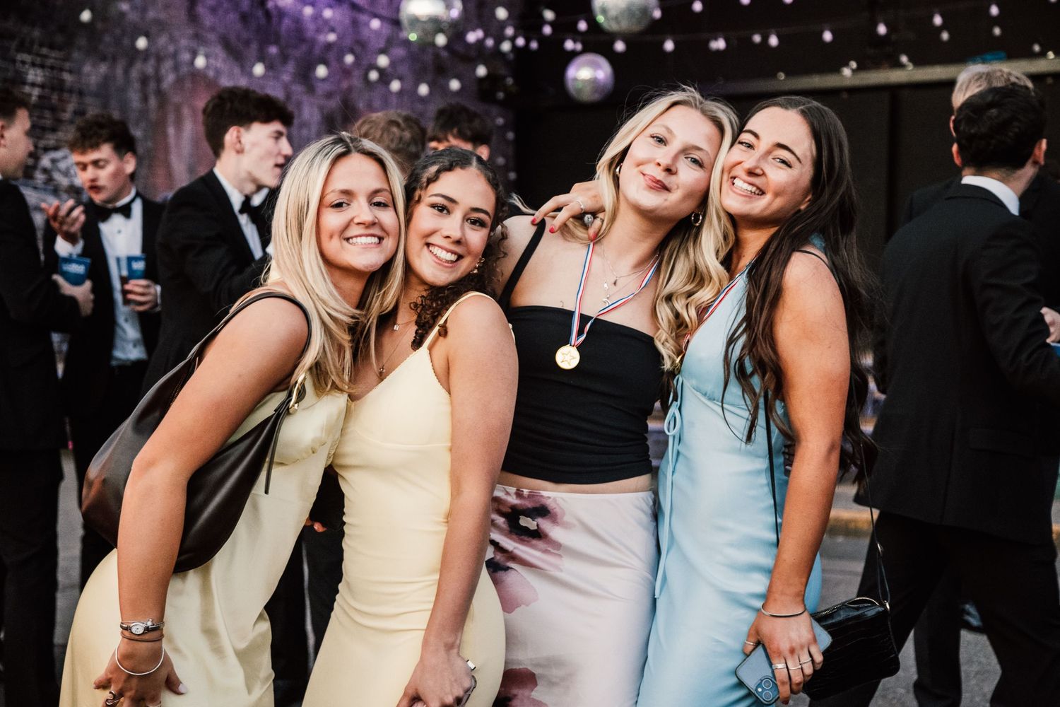 Wedding party guests dancing and celebrating under twinkling lights at night.
