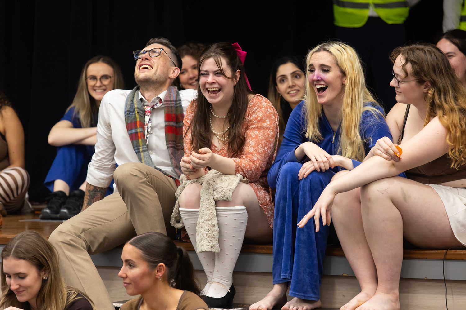 A lively audience reacts with laughter during a theatrical performance.
