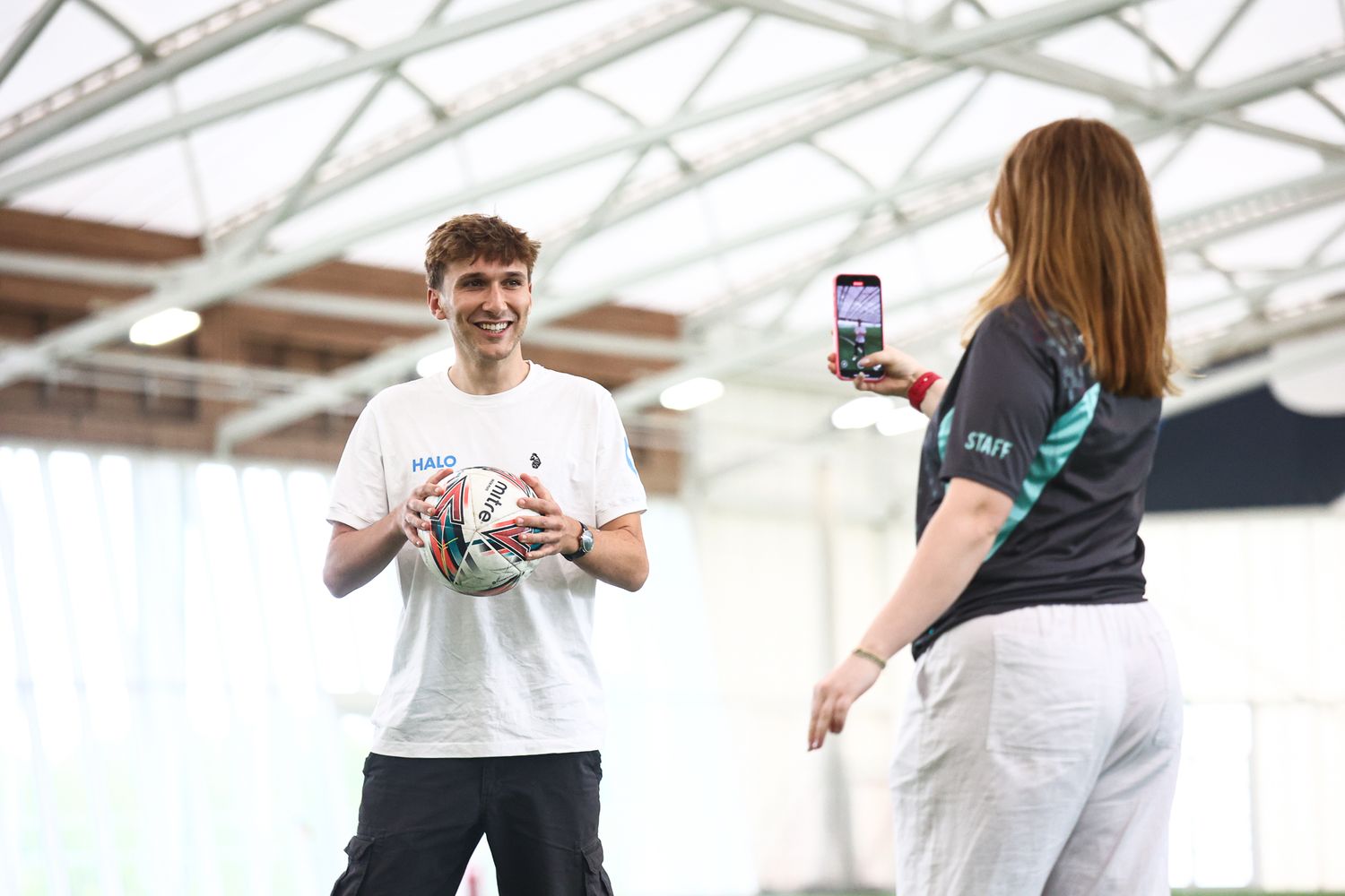 Athletes interacting and taking photos in indoor sports facility.
