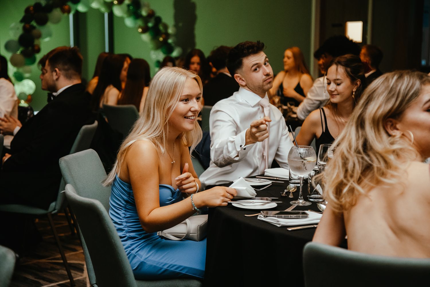 Wedding guests engaged in lively conversation at a reception table during dinner.