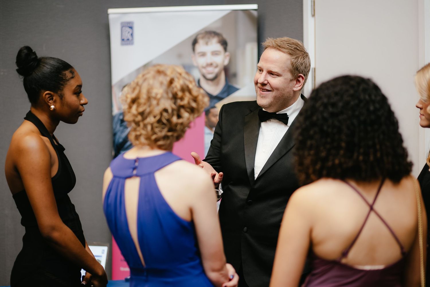 Formal event attendees engaged in conversation at an elegant indoor gathering.