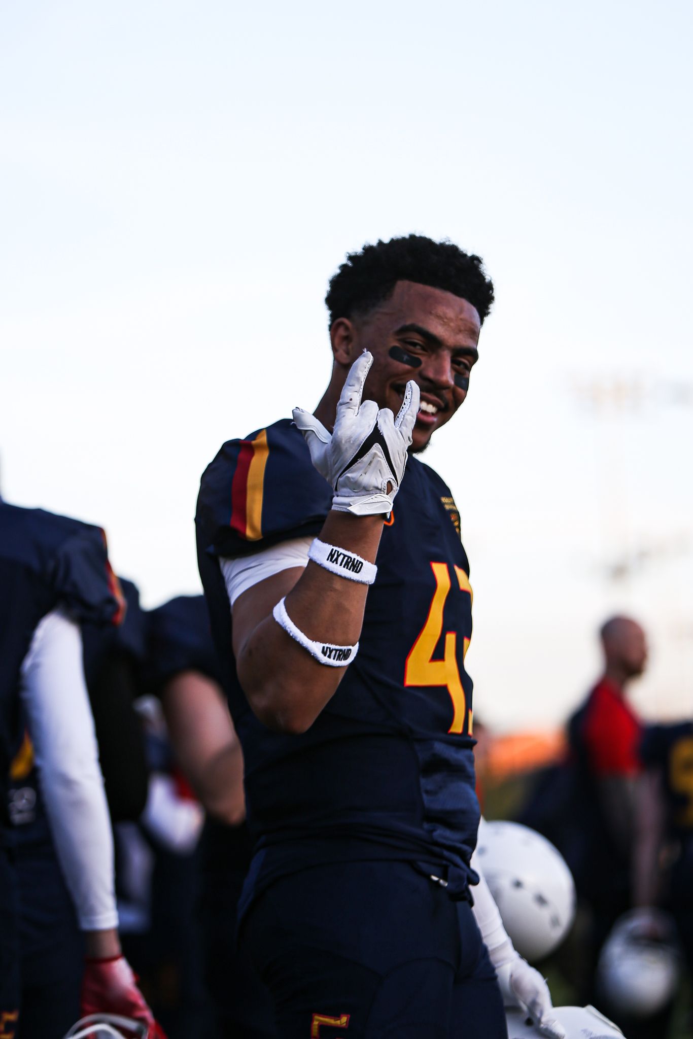 Football player in navy uniform with gold accents reacts emotionally during game.