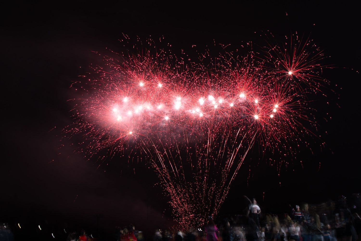 Red fireworks burst across the night sky in a dazzling display of pyrotechnic celebration.