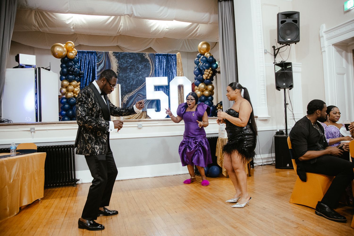 Party venue decorated with large light-up numbers and gold balloons for 50th celebration.