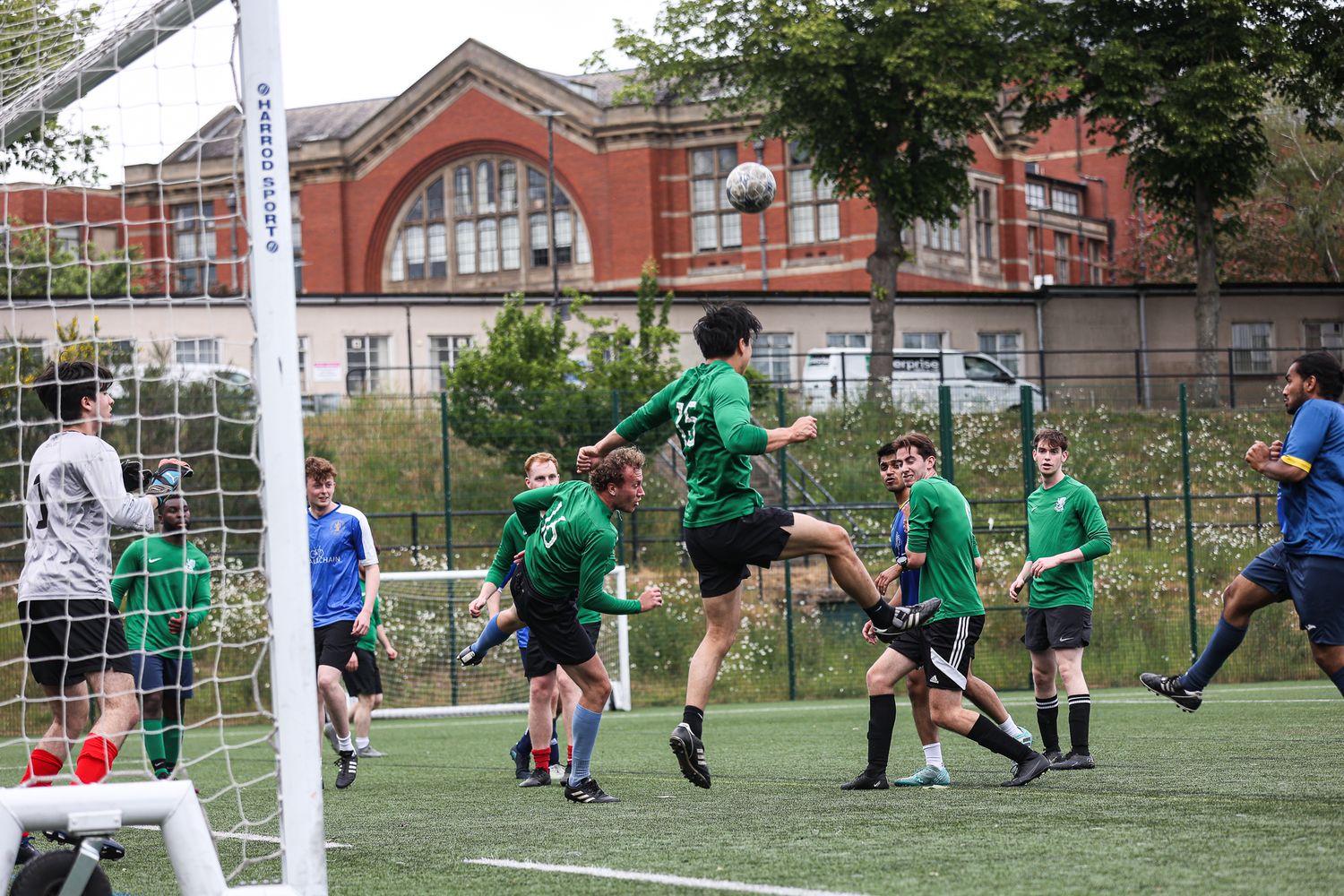 Soccer goalkeepers practicing diving saves in front of the goal posts.