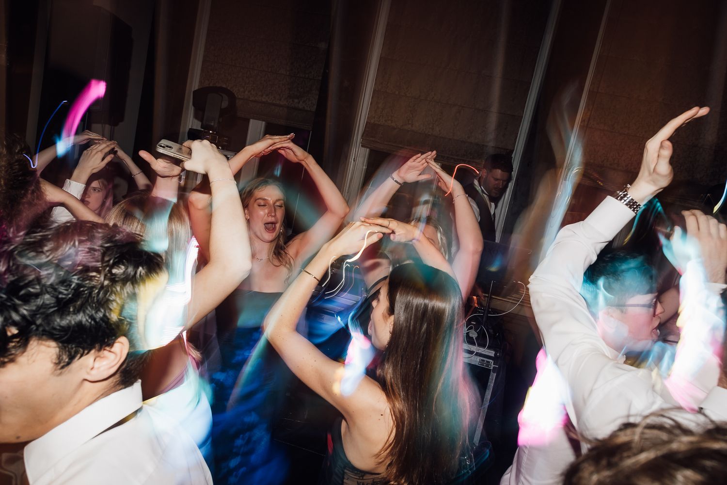 Colorful dance party with people dancing under pink lighting.