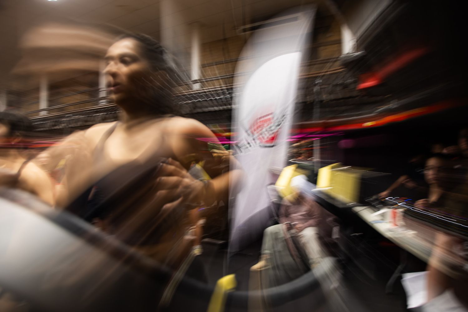Blurred motion shot of athletes training in a dimly lit indoor facility.