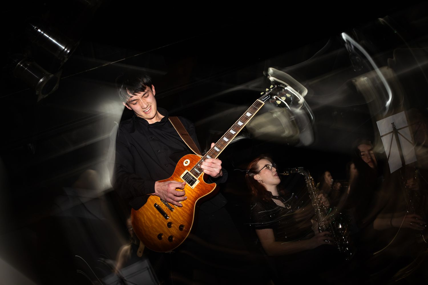 Close-up of an electric guitar being played during a darkly lit performance.