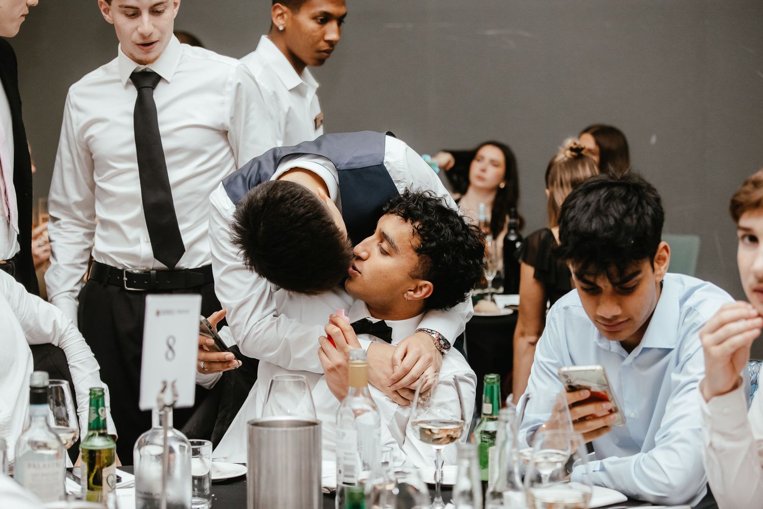 Group of attendees in formal attire gathered around tables at an evening celebration.