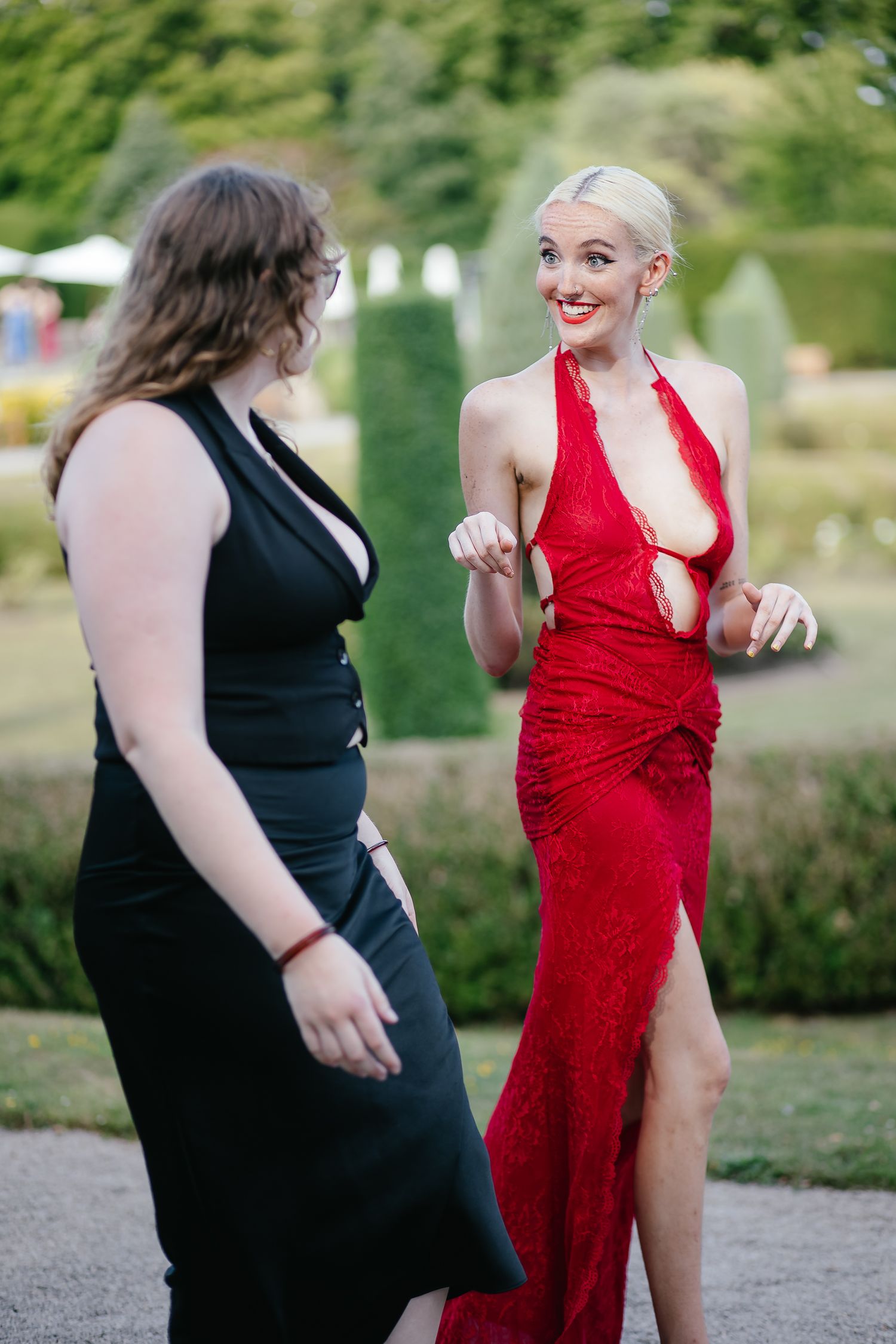 Two people in contrasting black and red dresses dancing together in a garden setting.