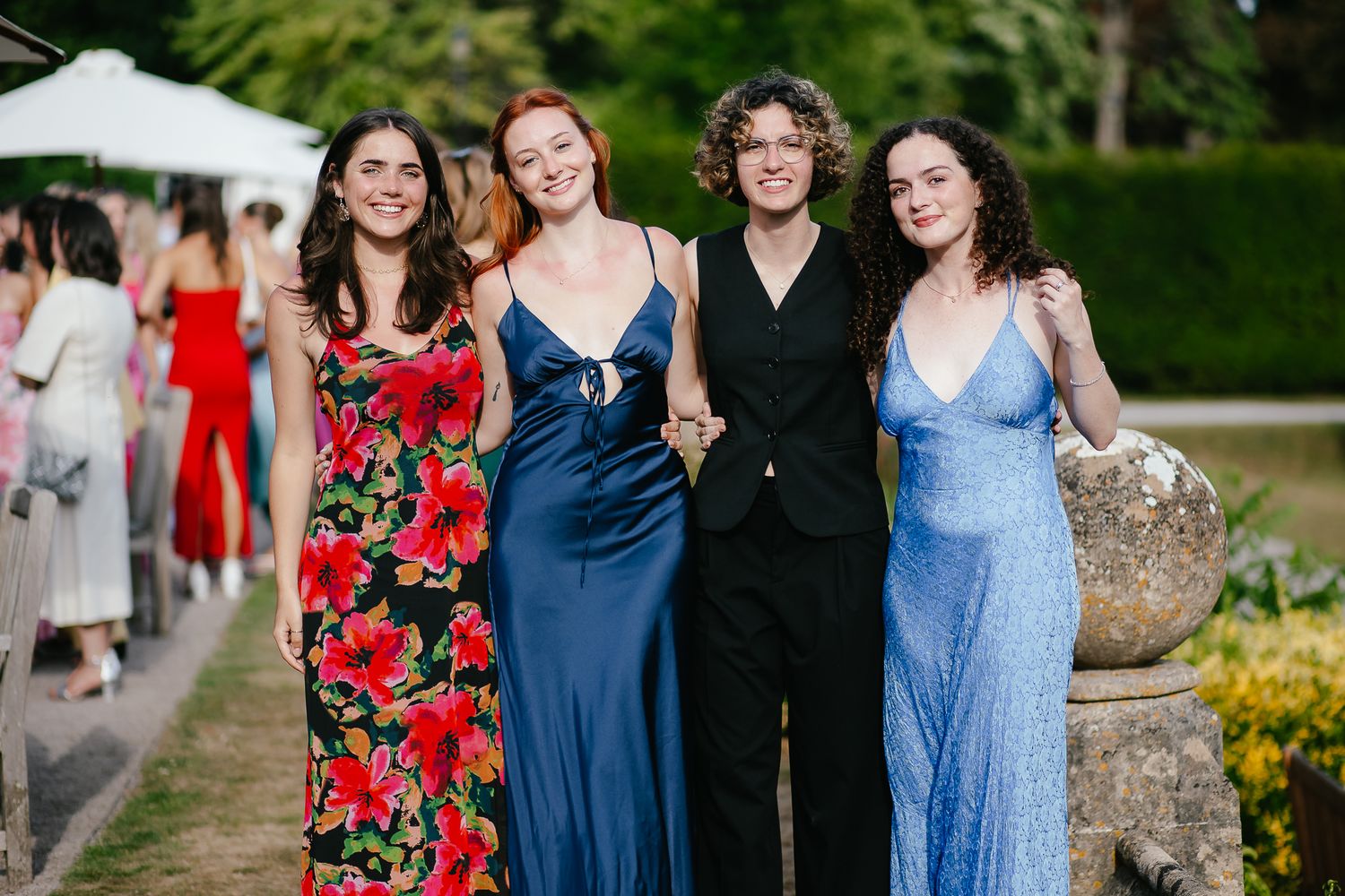 Bridesmaids in colorful dresses pose together during outdoor wedding photos.