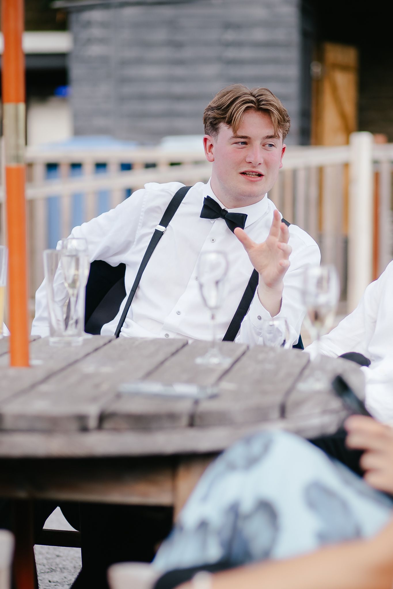 Young attendants in formal attire with white shirts and suspenders at an outdoor event.