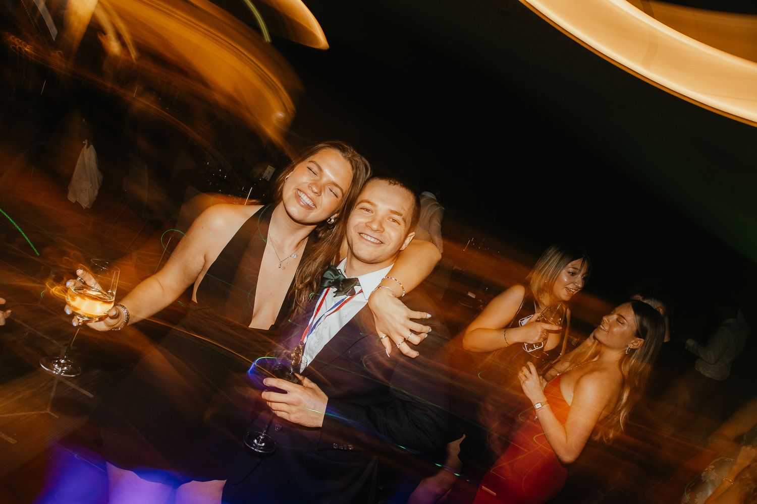 Partygoers dancing and celebrating in a warm-lit venue during a special occasion.