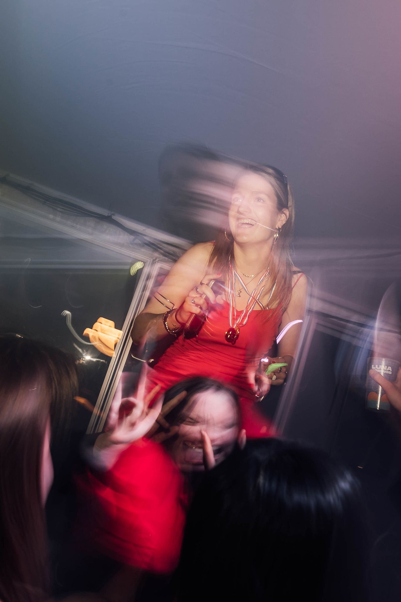 Motion blur captures energetic dancers in red outfits performing on a dark stage.