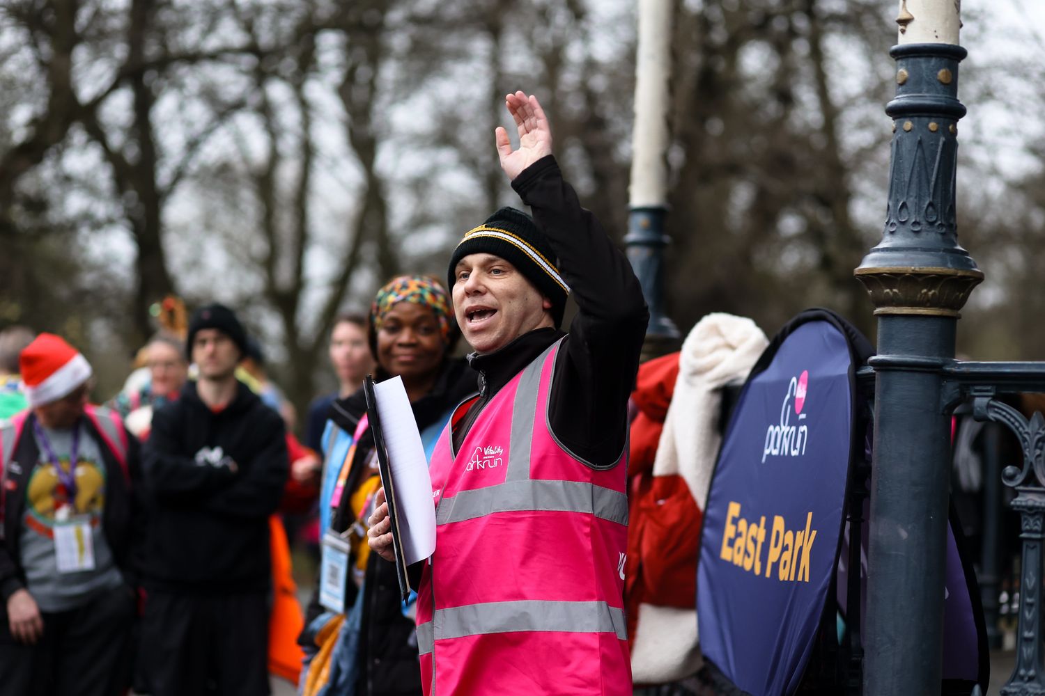 An enthusiastic event volunteer in high-vis gear cheering on participants during a community event.