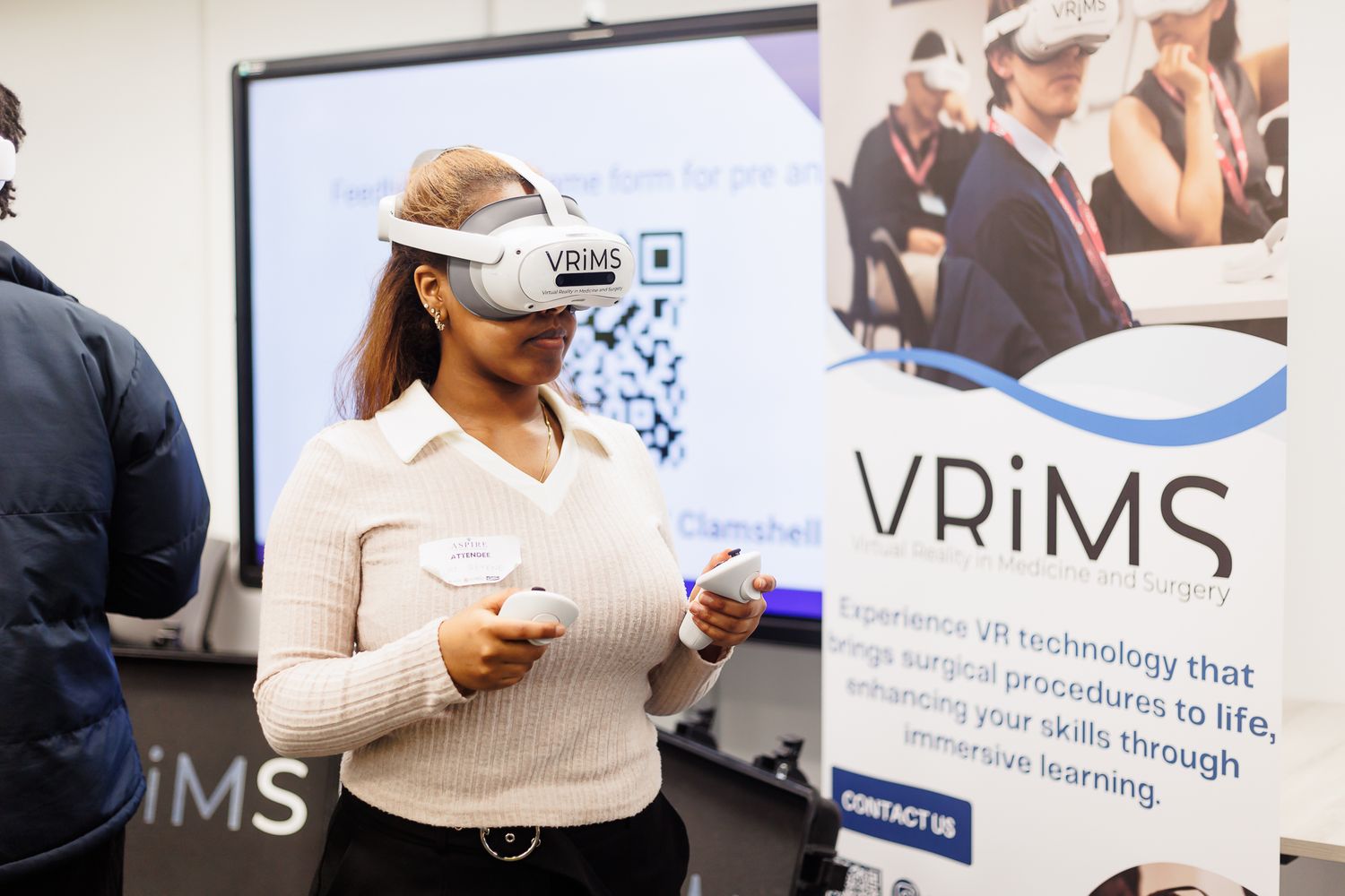 Person demonstrates VR technology at a VRIMS booth during an educational event.