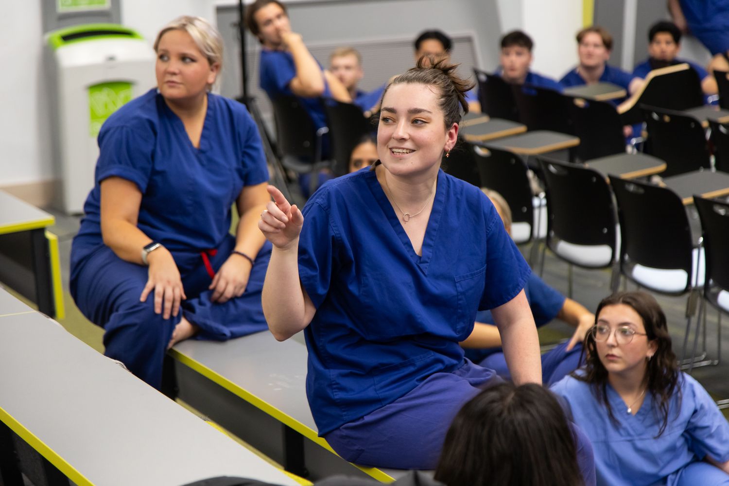 Healthcare workers in scrubs smile and engage during a training session.