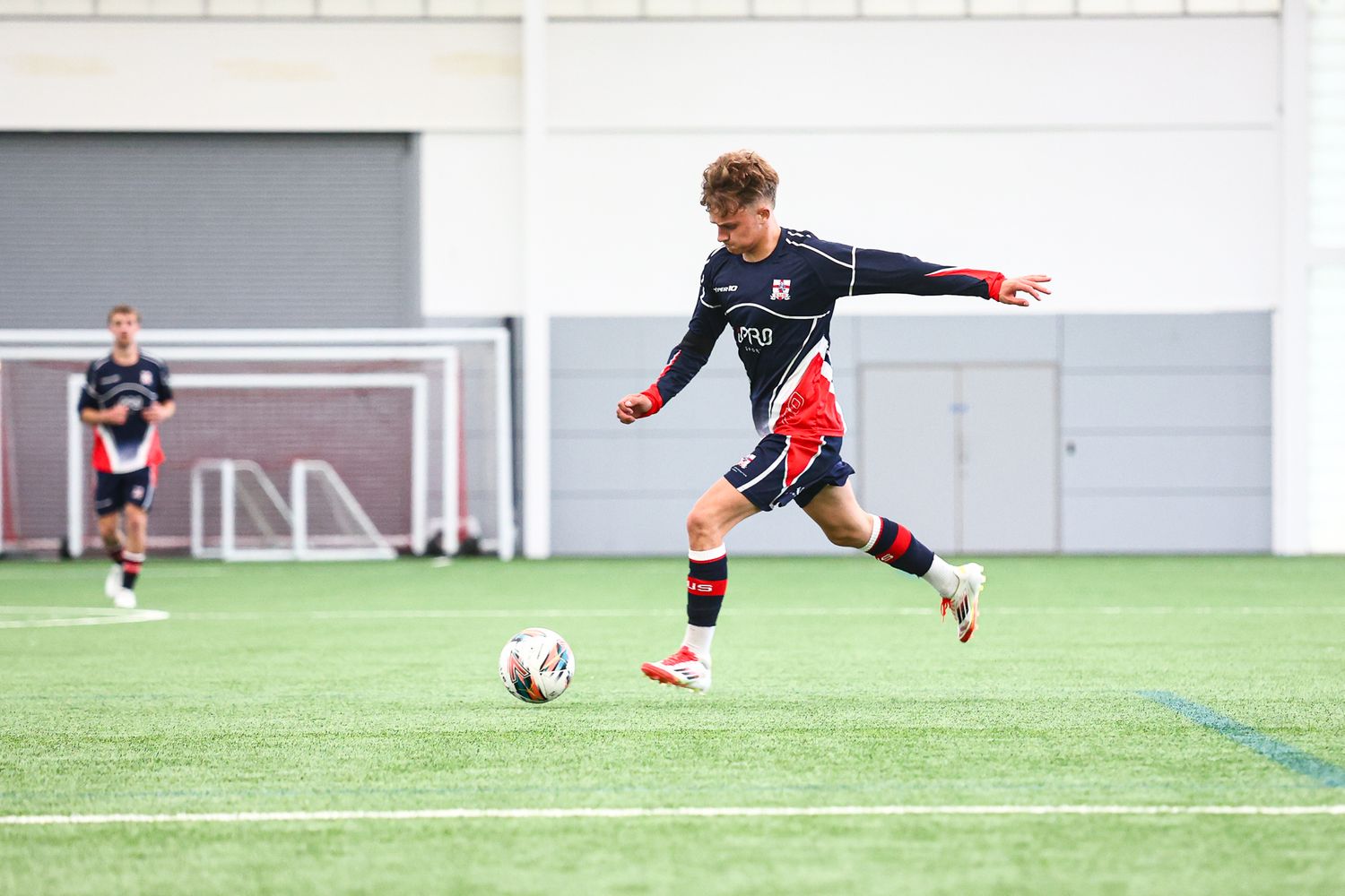Soccer players practicing ball handling skills on indoor turf field.