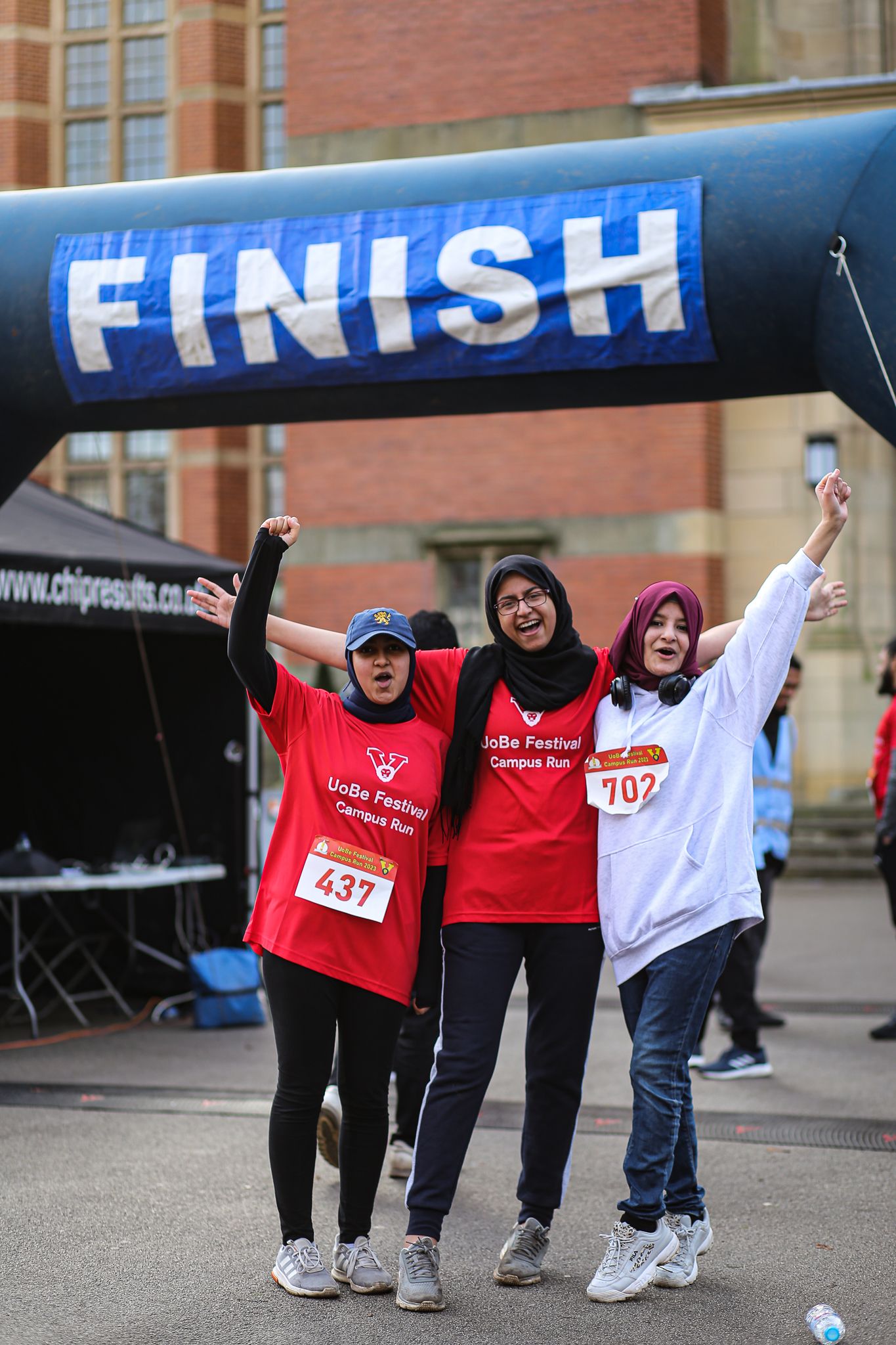 Athletes celebrate at the finish line of a race wearing red and white jerseys.