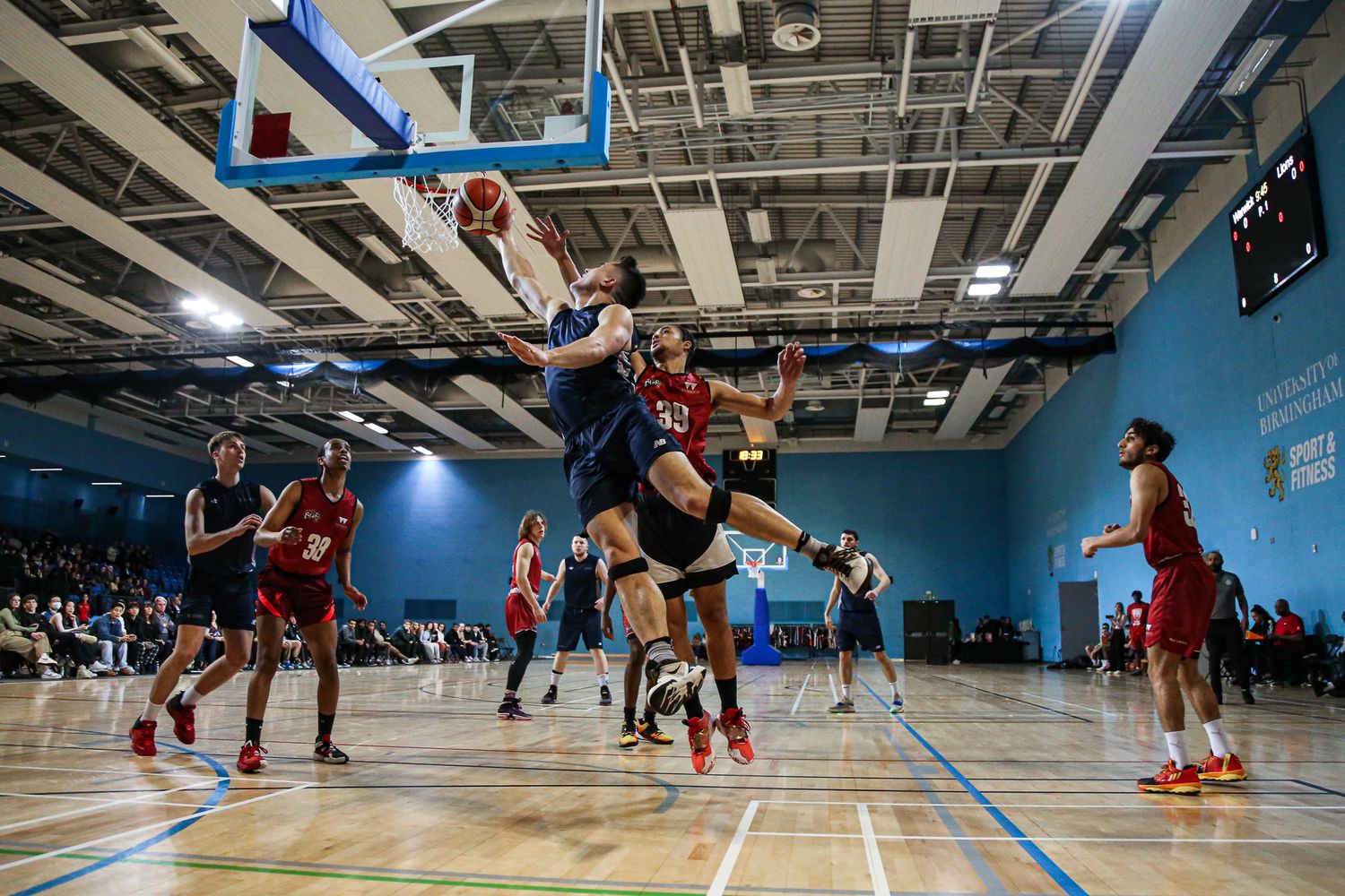 Basketball players compete on an indoor court under bright lights during an intense game.