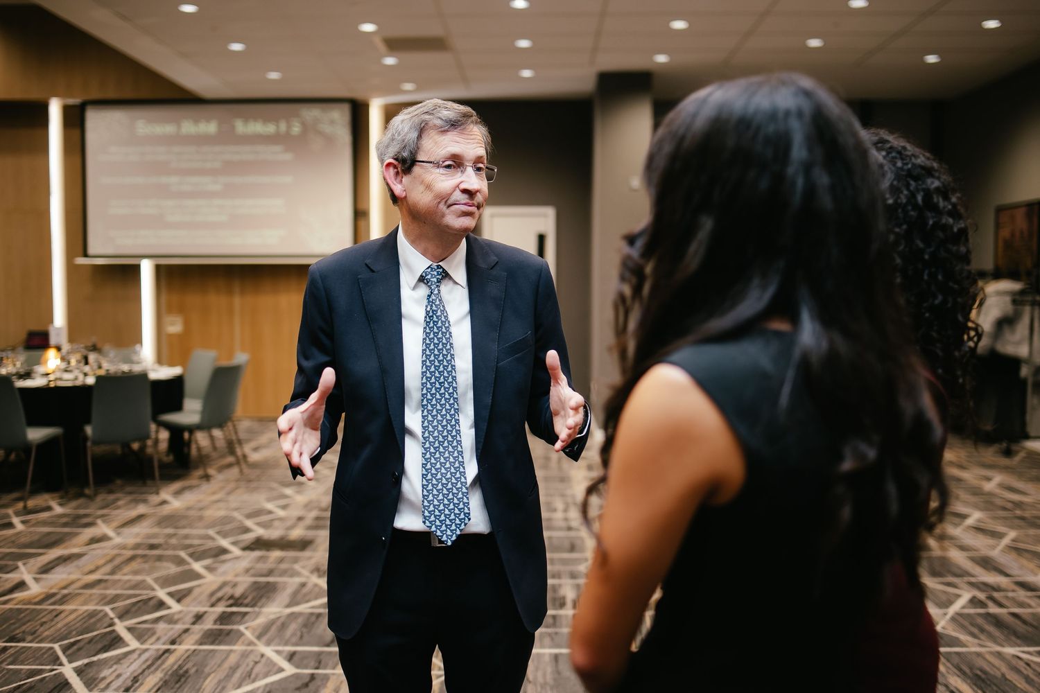Professional business people engaged in conversation during a conference or networking event in a hotel ballroom.