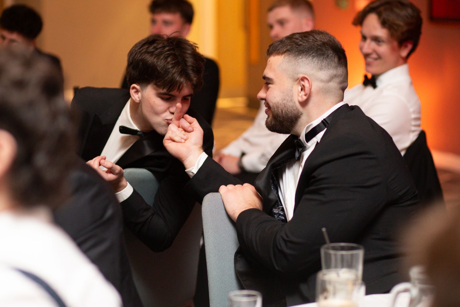 Evening banquet guests engaged in lively conversation under warm lighting.