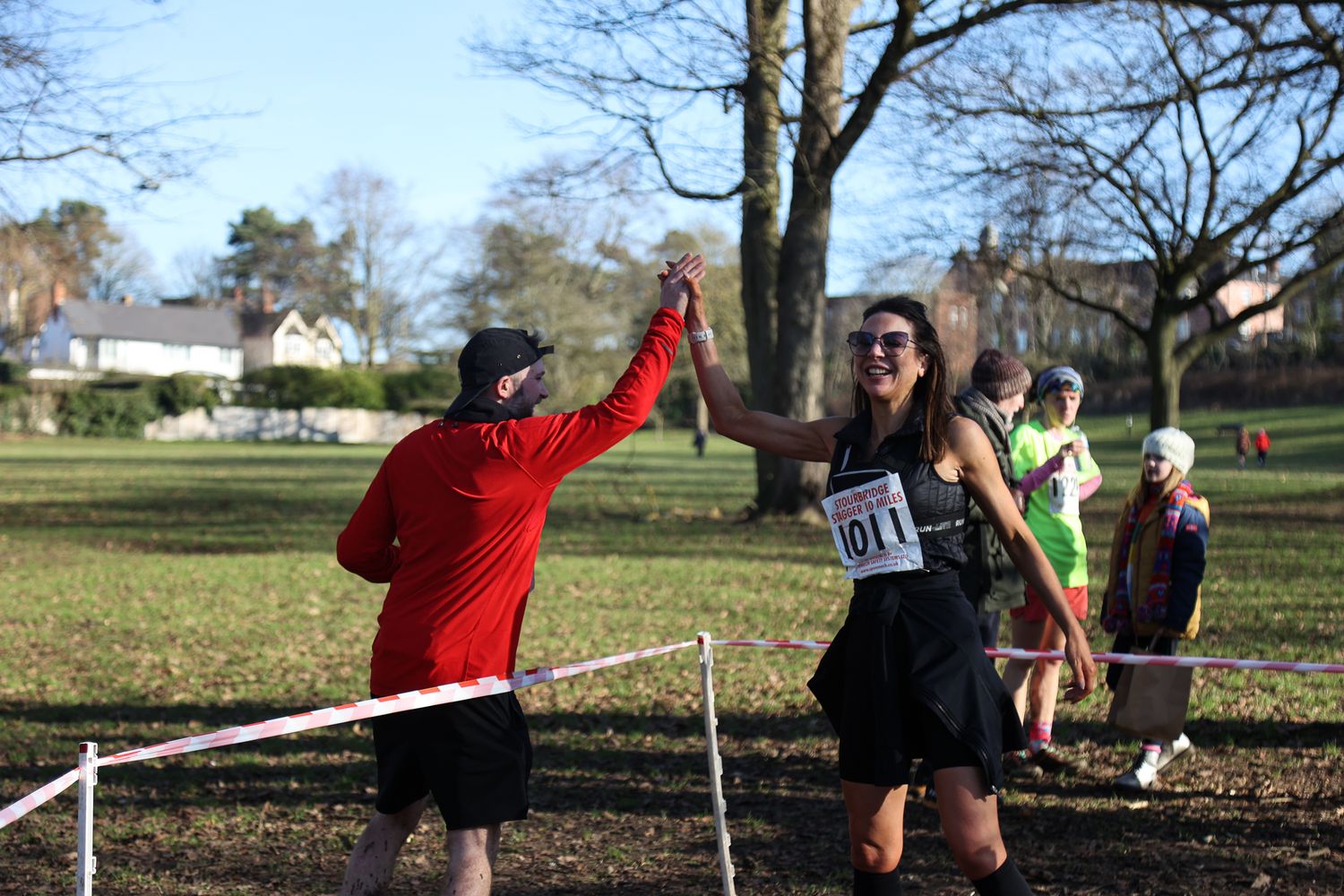 Athletes competing in a cross country race through a park with bare winter trees.