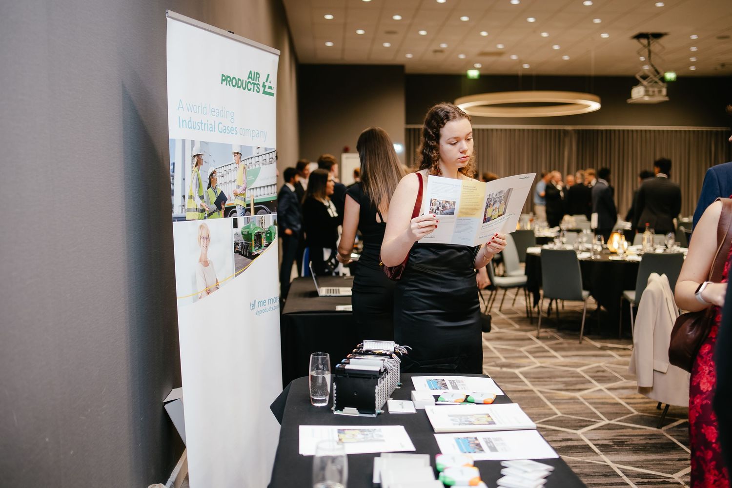 Business professionals networking and viewing presentation materials at a corporate conference event.