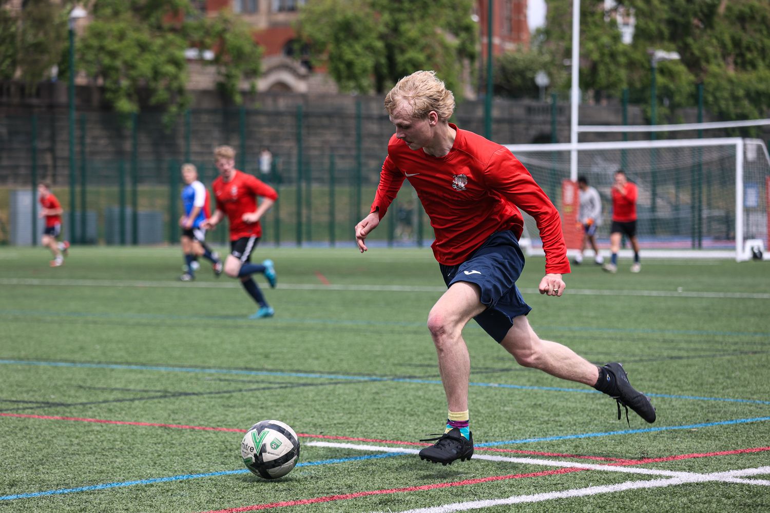 A sequence of soccer players making sliding tackles on an outdoor turf field during a match.