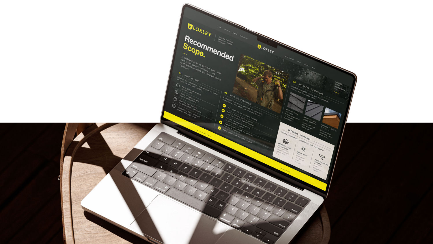 Open laptop on a wooden desk displaying a dark website page titled Recommended Scope with yellow accents and project images.