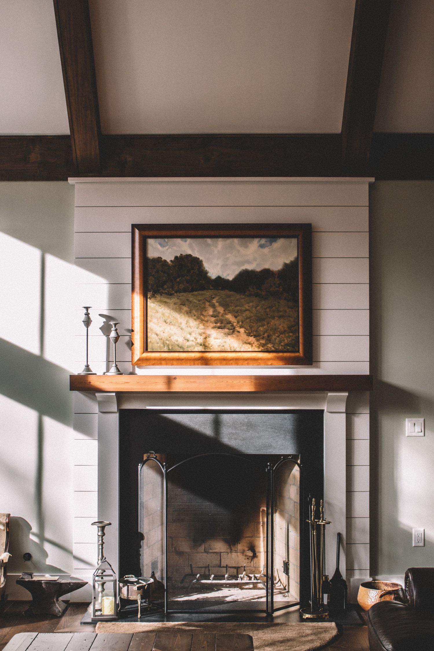 Modern interior with dark walls features shiplap paneling, floating shelves, and sunlight casting dramatic shadows.