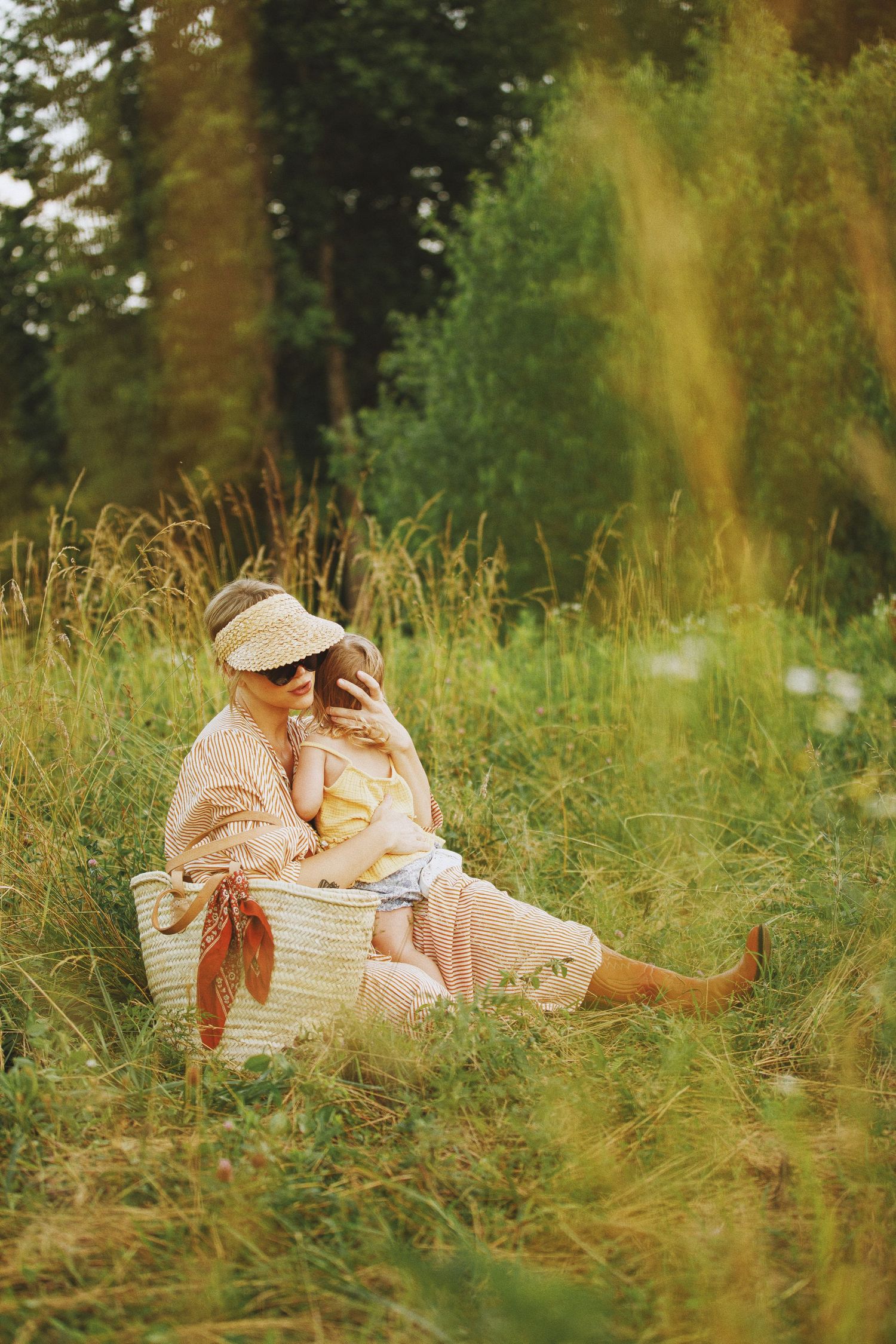 A mother and child sitting together in a lush green meadow, sharing a tender moment during a summer picnic.