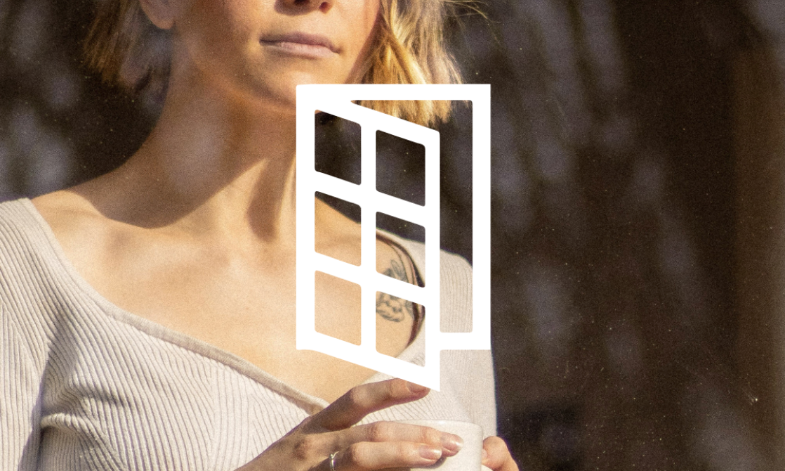 Person in white holding a geometric photo frame against a dark background.