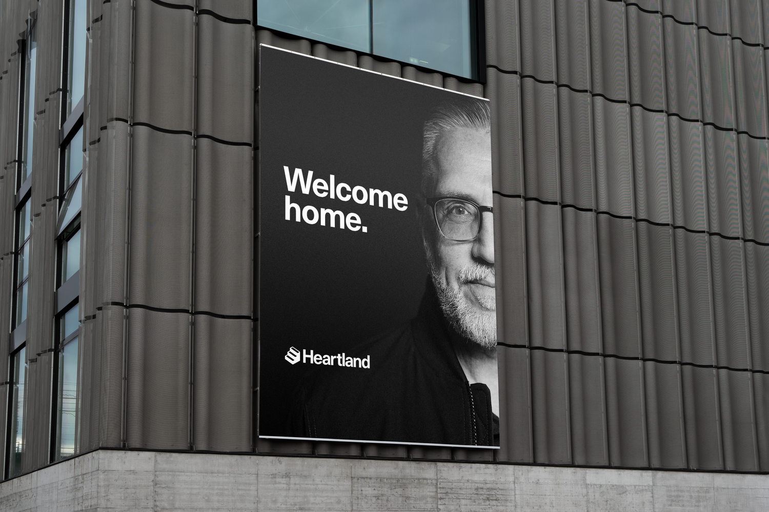 Black and white welcome home advertisement displayed on modern building exterior.