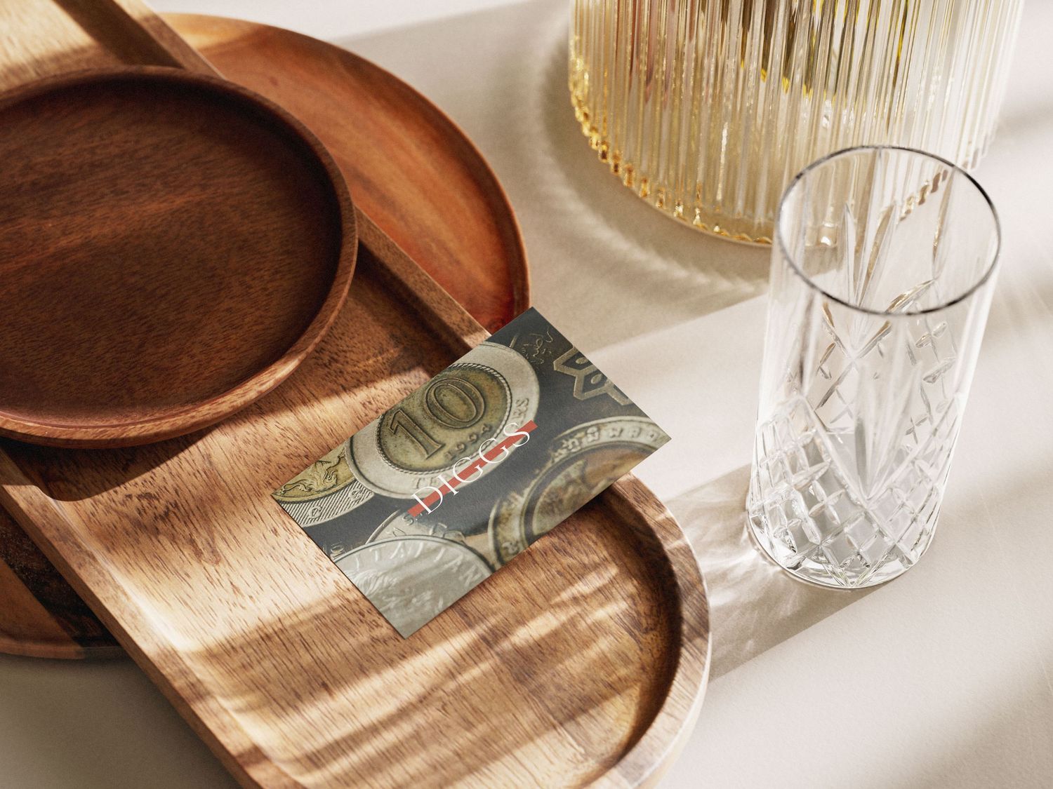 Wooden serving tray with small bowls, a $10 bill, crystal glass, and gold vase on a white surface.