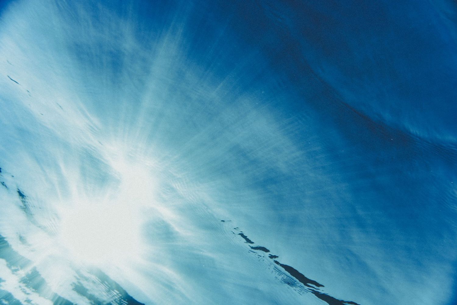 Dramatic blue sky with sunburst and wispy cirrus clouds creating an ethereal atmosphere.