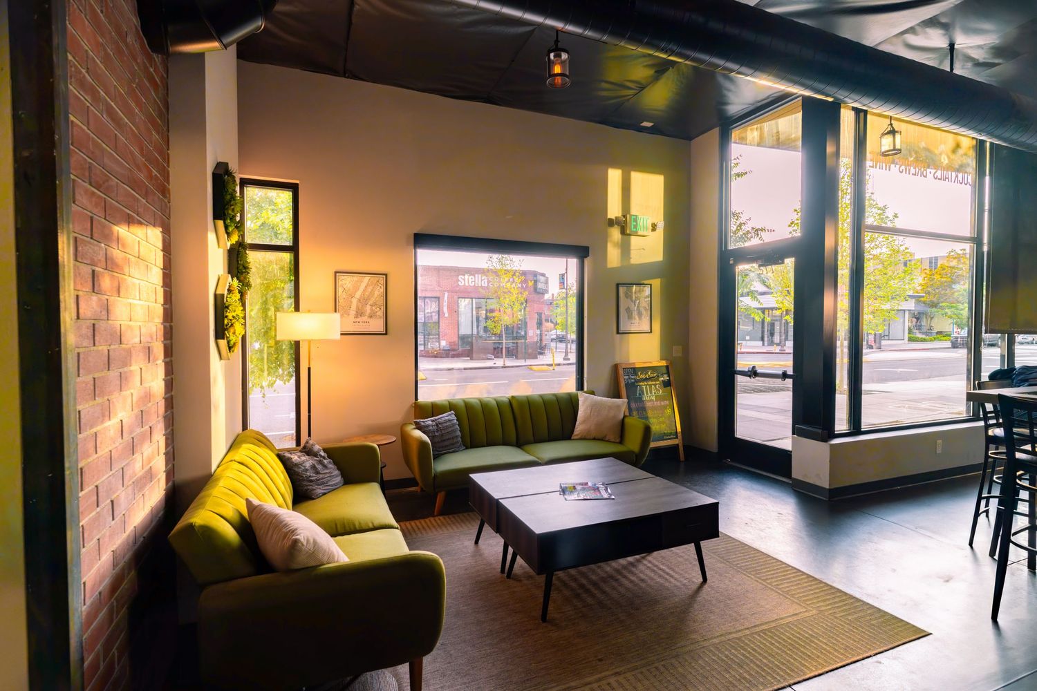 Cozy lounge area with olive green sectional sofa and modern decor in an industrial-style space.