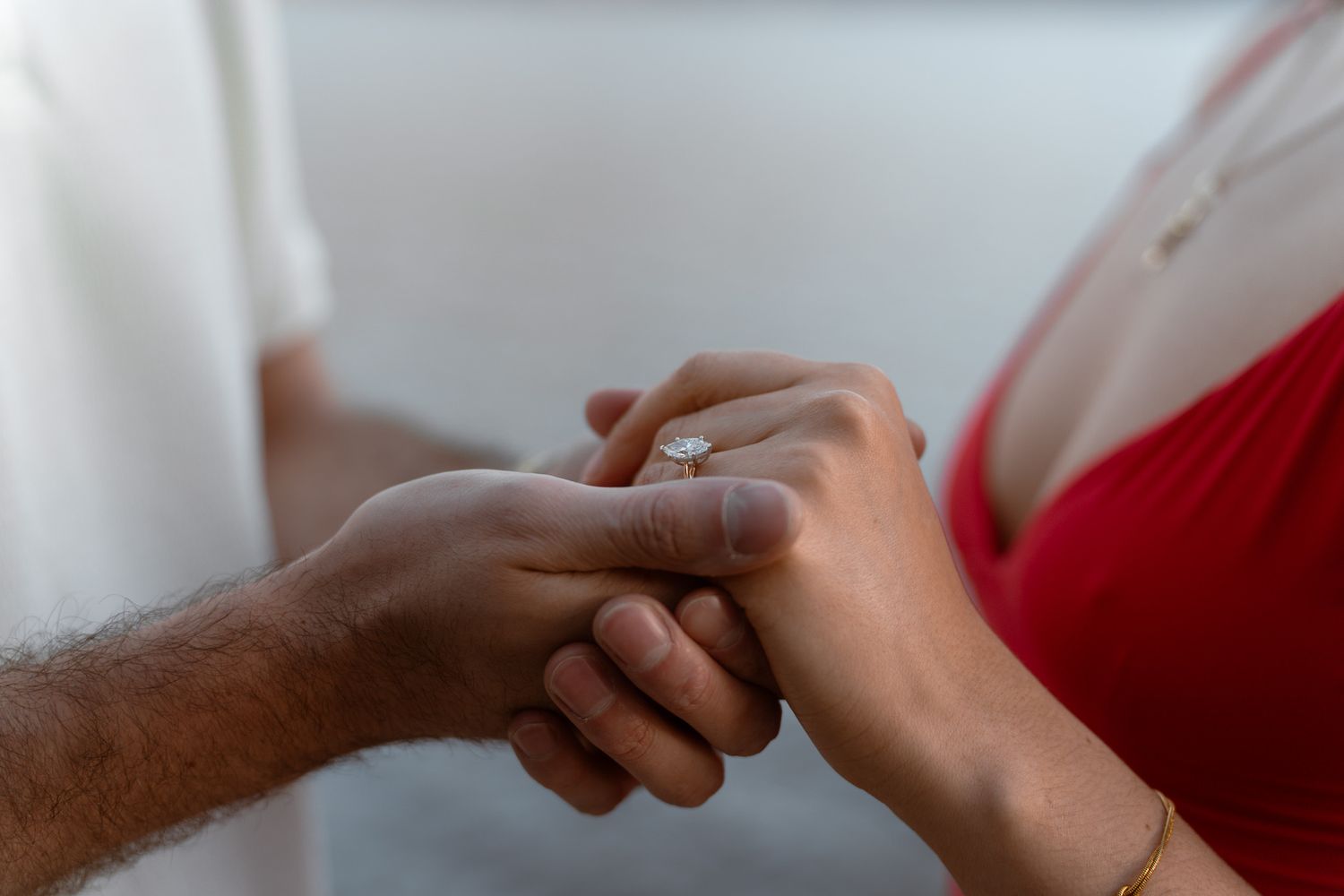 Close-up of hands touching during a physical therapy or massage treatment on a red background.