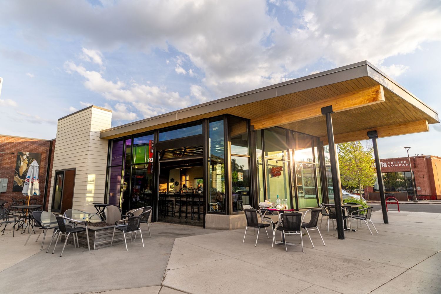 Modern restaurant exterior with outdoor patio seating and contemporary architectural design at sunset.