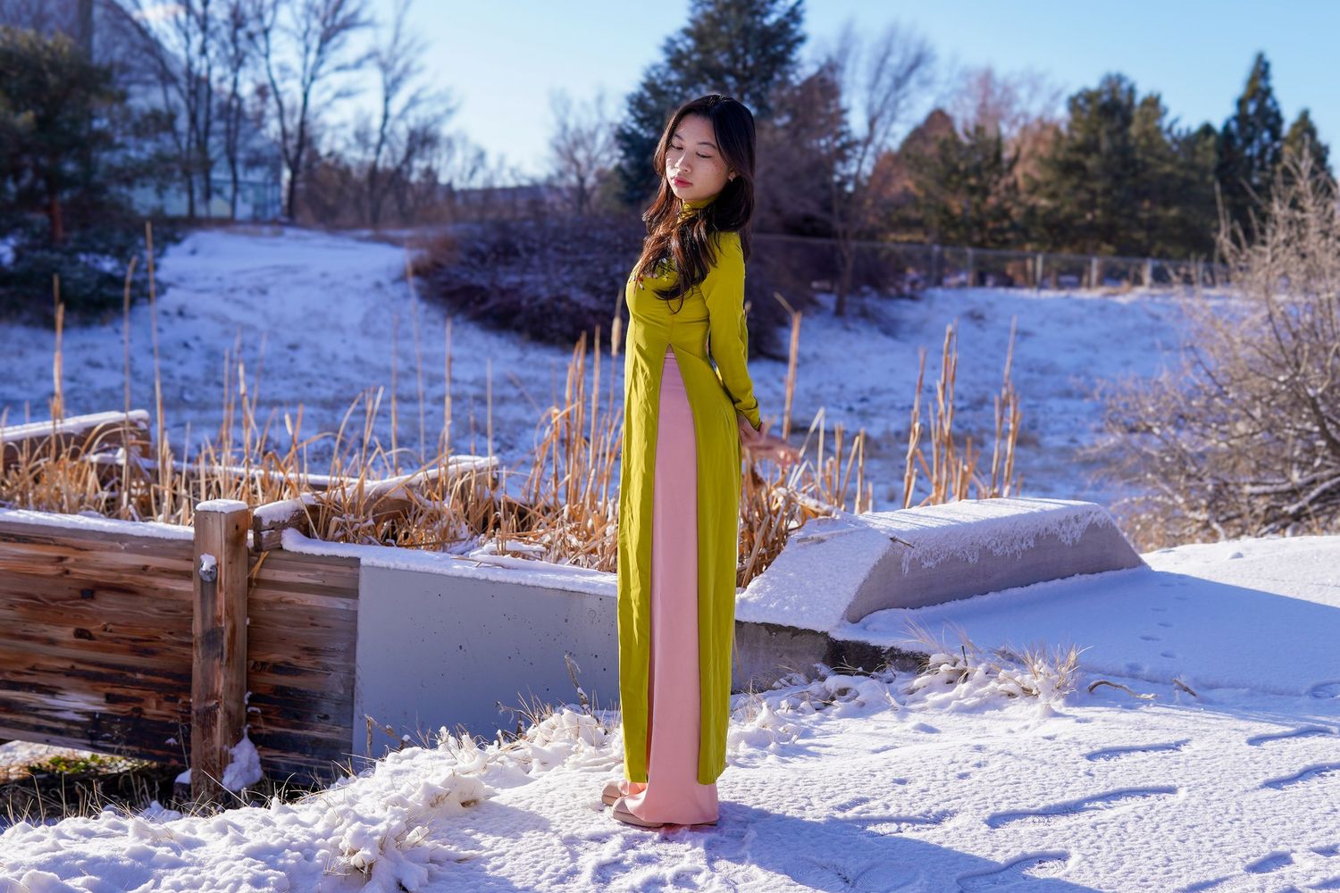 Person in bright yellow coat posing in snowy winter landscape.