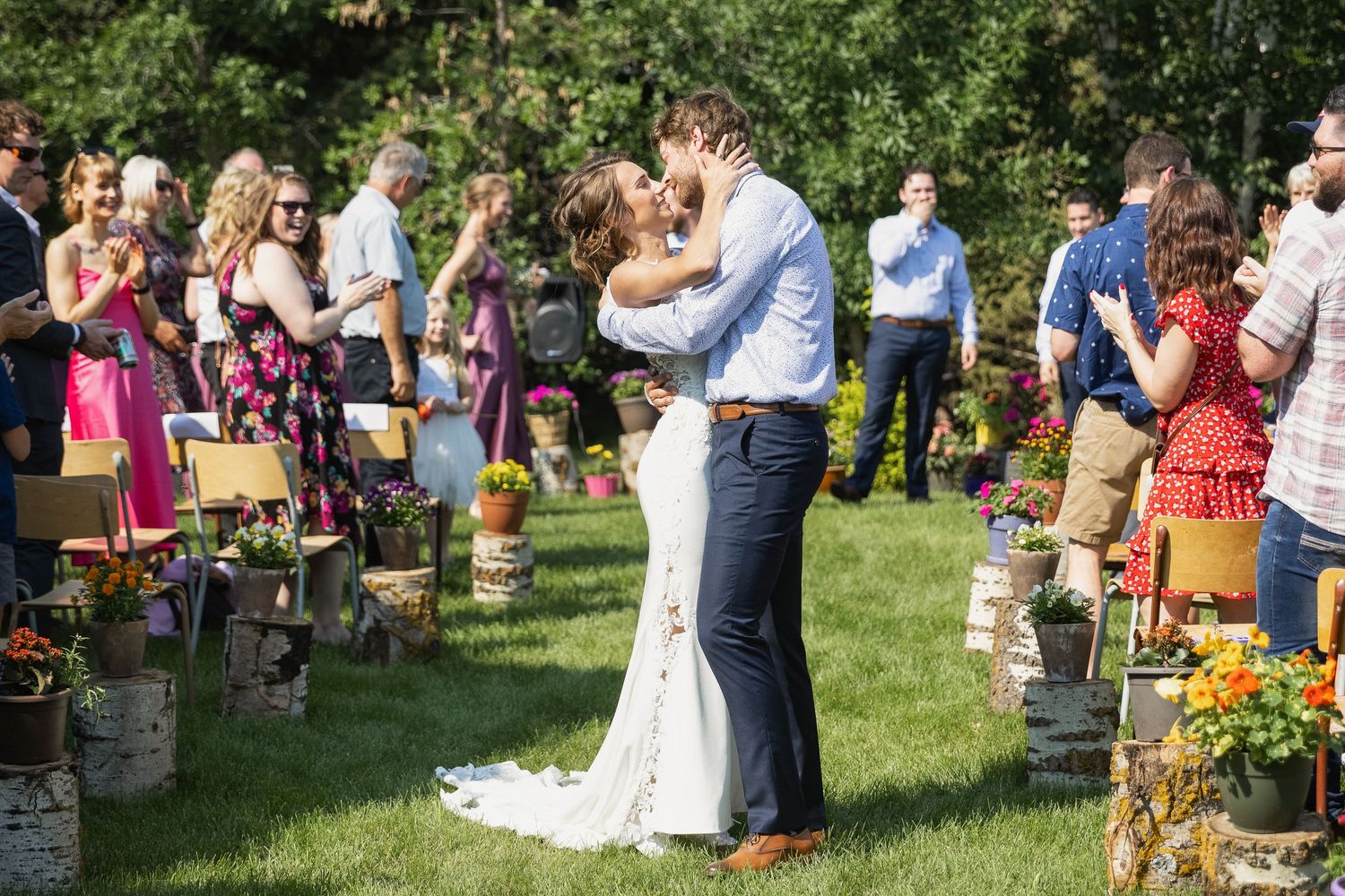 Bride and groom stop in the aisle after their ceremony for a kiss surrounded by their cheering guests.