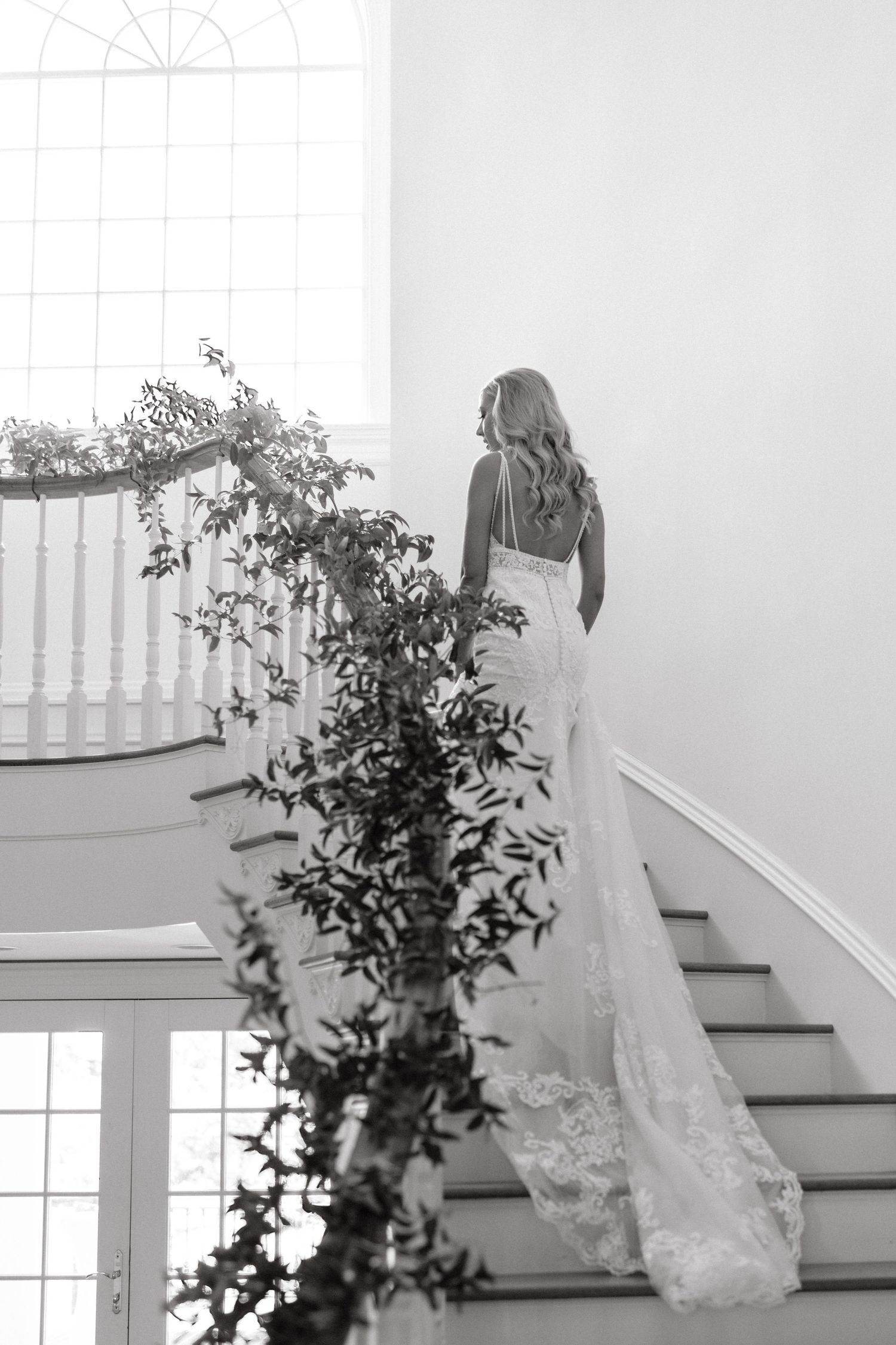a bride walks up the stairs at her indoor wedding venue, showing off the back detailing and train of her wedding dress