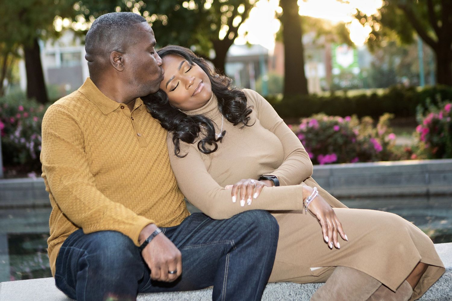A couple sits together outdoors sharing a tender moment in warm autumn clothing.