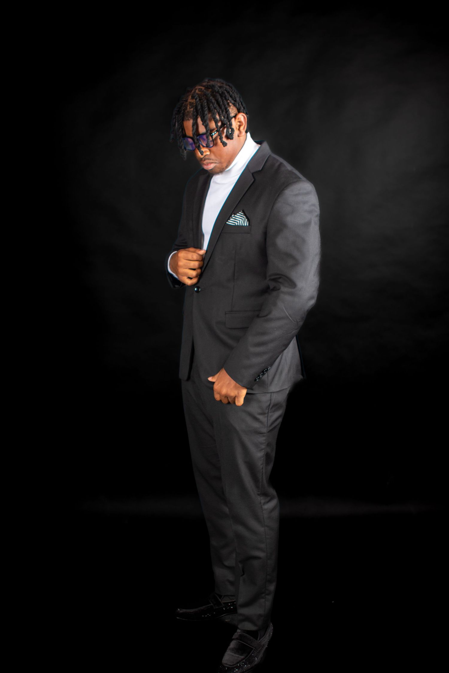 Professional portrait against dark background featuring sharp suit and formal attire.
