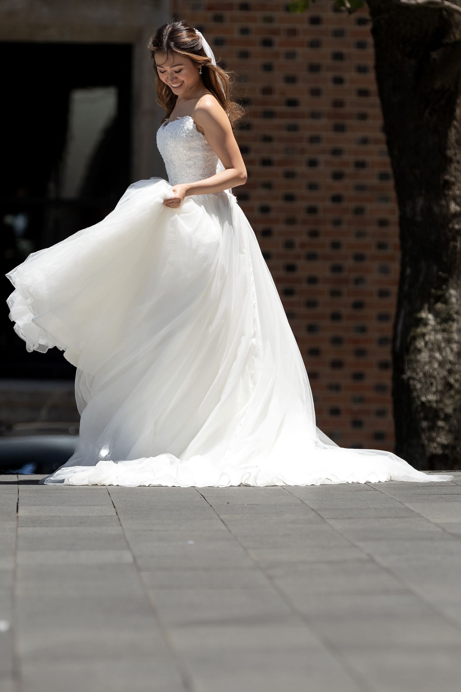 Bride twirling in a stunning white ballgown wedding dress outdoors in natural sunlight.