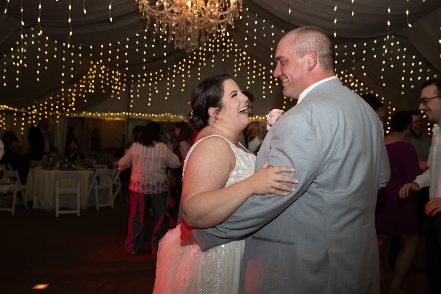 Bride and groom share first dance under twinkling fairy lights at elegant wedding reception venue.