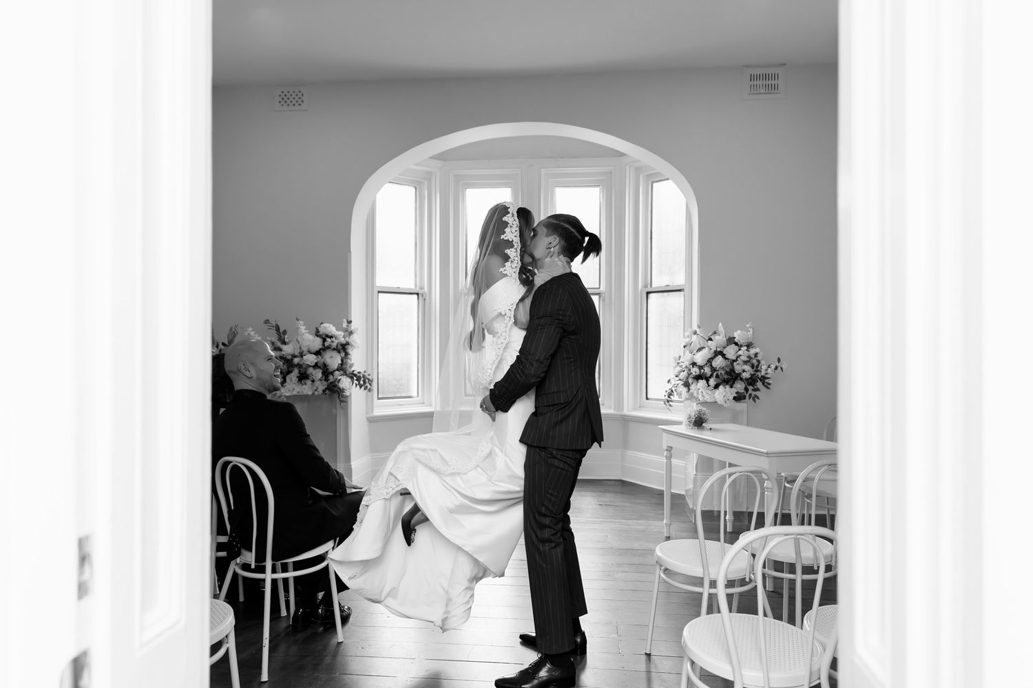 Black and white photo of a bride and groom sharing a romantic dance in an elegant wedding venue.