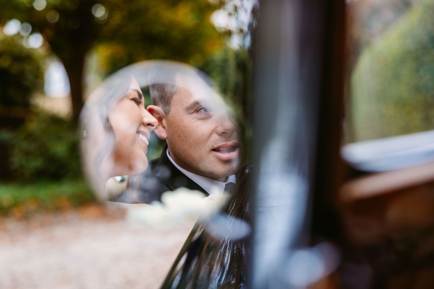 A couple shares a romantic moment during their wedding day in a convertible vintage car.