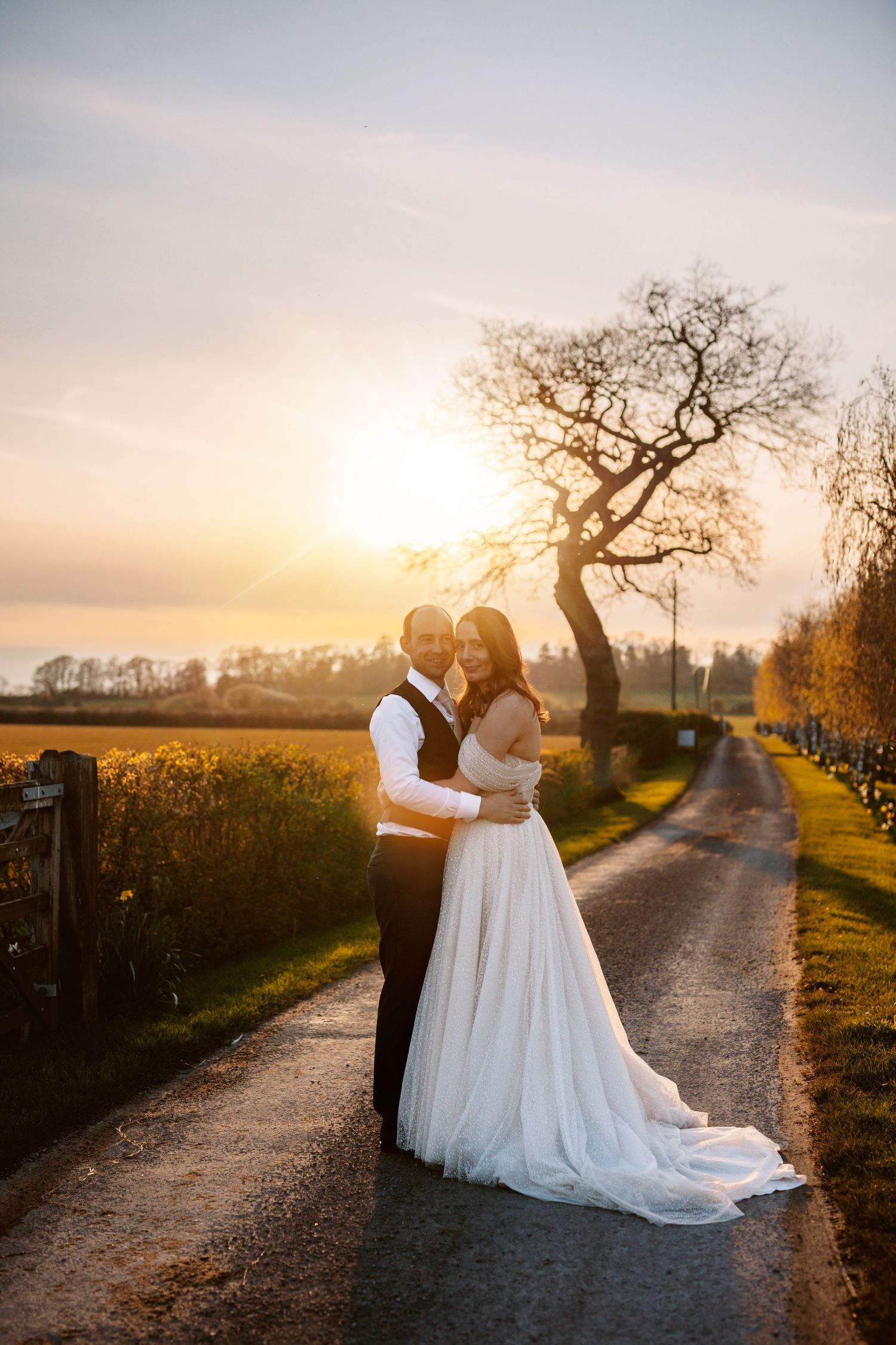A romantic sunset wedding portrait on a rural path with trees silhouetted against the sky Stratton Court Barn.